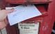 A ballot paper is posted into a red post box