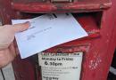 A ballot paper is posted into a red post box